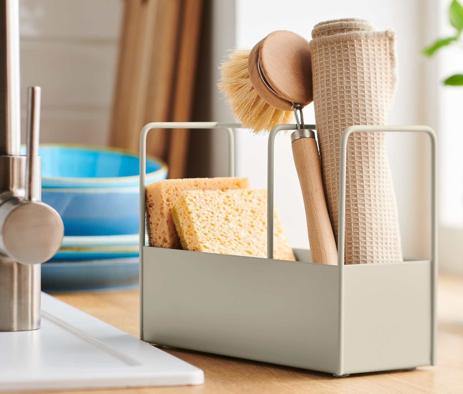 Stojak na przybory ze zmywakami, szczotką i ścierką na blacie kuchennym.