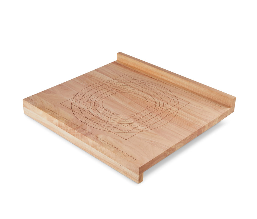 Drewniana stolnica z zaznaczonymi okręgami i prostokątami do pracy z ciastem.