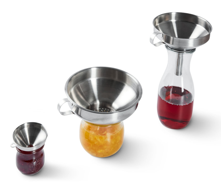 Lejki ze stali nierdzewnej stoją na słoikach z dżemem.