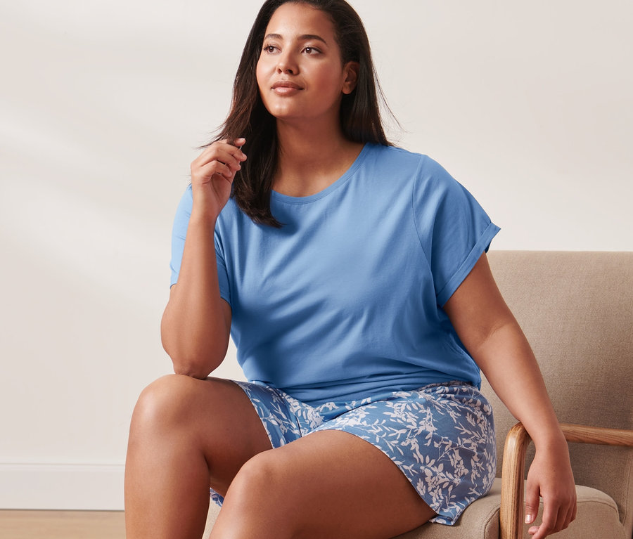 Kobieta siedzi na krześle w piżamie z koszulką i spodenkami.