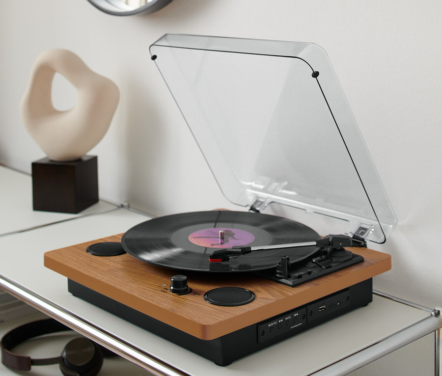 Gramofon »Dual DTR 61« z wbudowanymi głośnikami stoi na białym stoliku z płytami winylowymi.