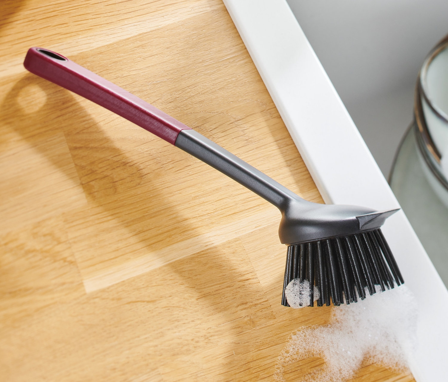 Szczotka do mycia naczyń ze skrobakiem leży na blacie obok zlewu.