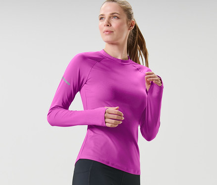 Kobieta w czarnych legginsach i neonowo malinowej koszulce funkcyjnej z długim rękawem biegnie.