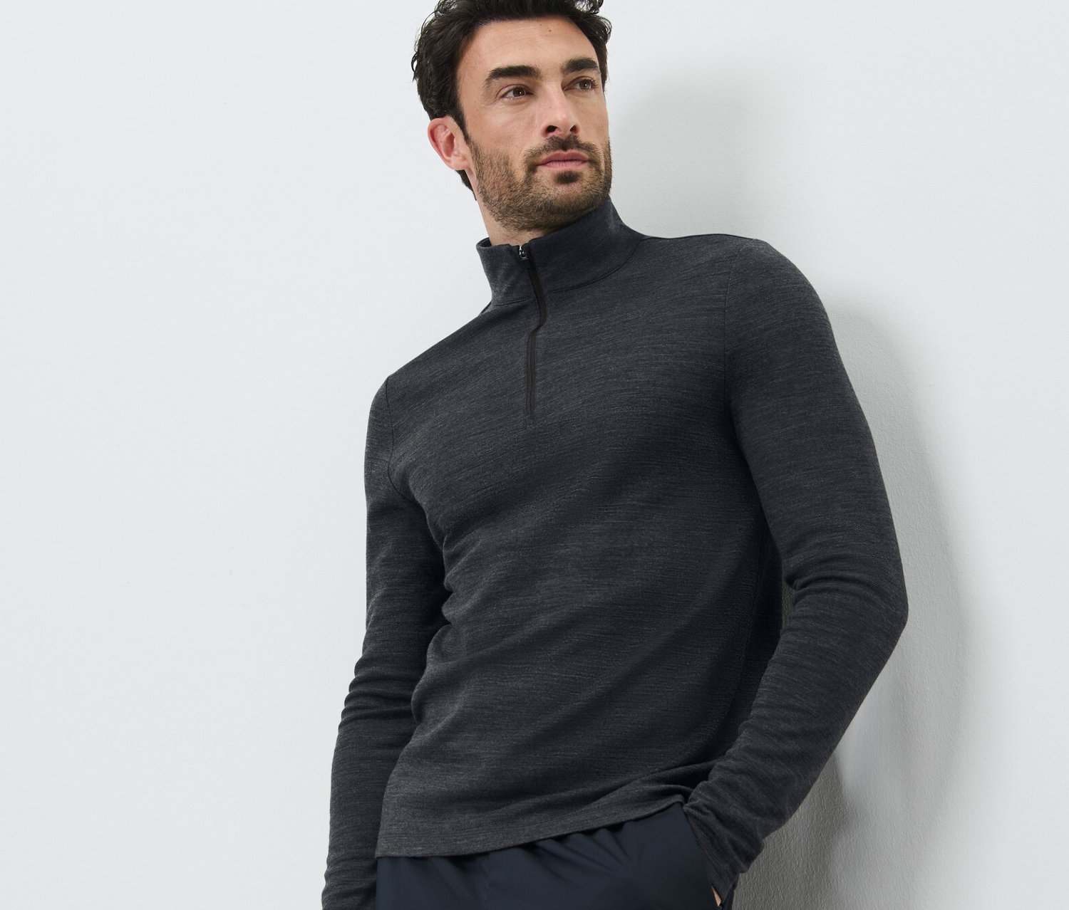 Mężczyzna pozuje na białym tle, ubrany w koszulkę funkcyjną z wełną z certyfikatem RWS i ciemne spodnie.