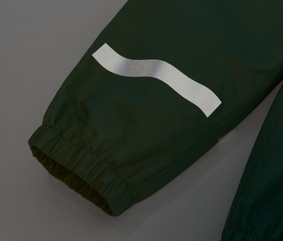 Zbliżenie na zielone spodnie przeciwdeszczowe z odblaskowym paskiem.