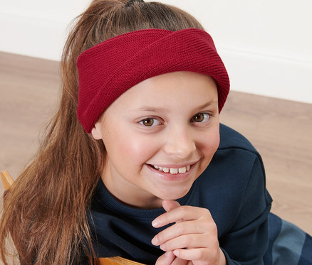 Dziewczynka siedzi na krześle i ma na sobie opaskę dzianinową.