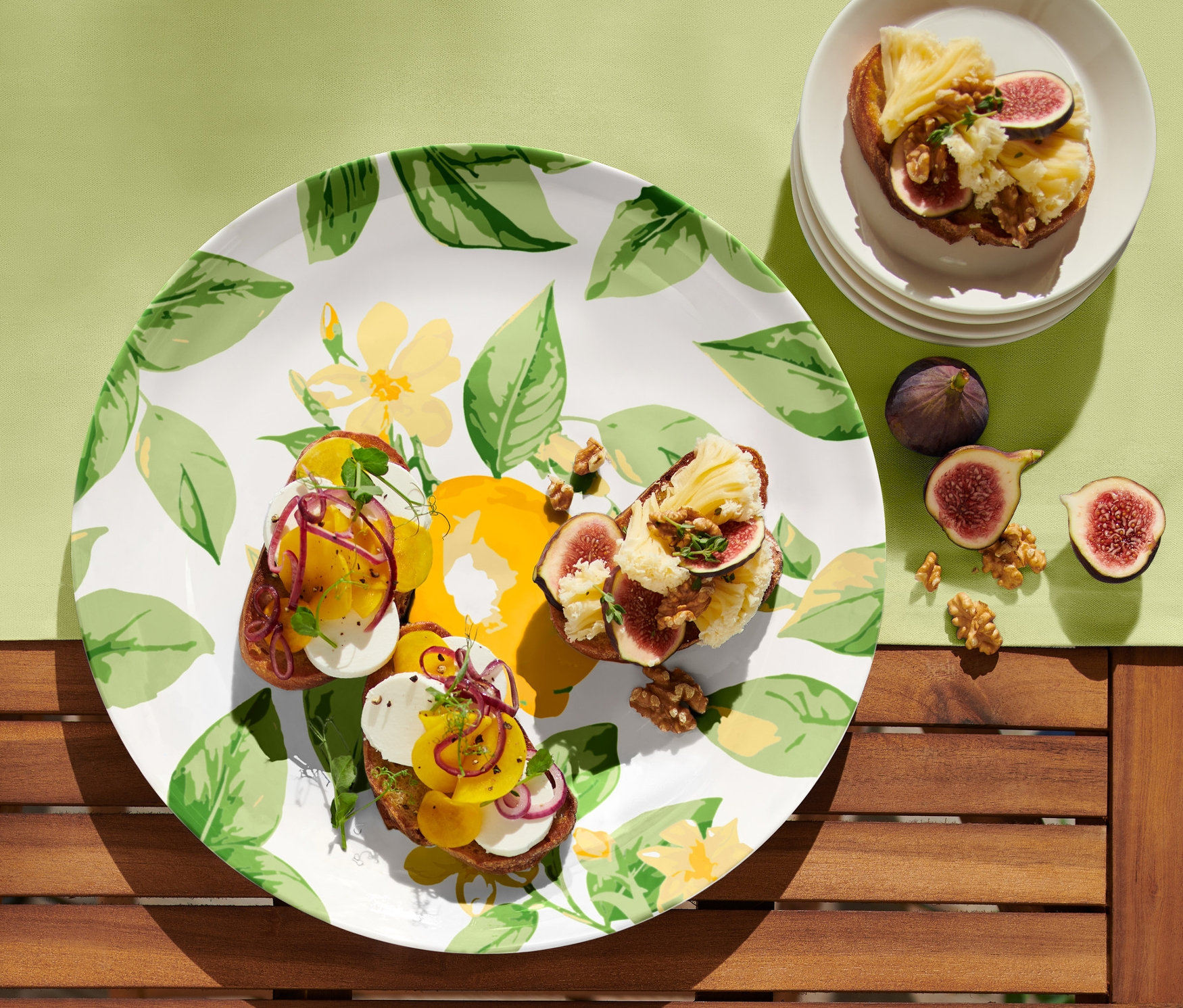 Na talerzu do serwowania leżą trzy tosty z figami i serem. Na stole leżą również figi i orzechy.