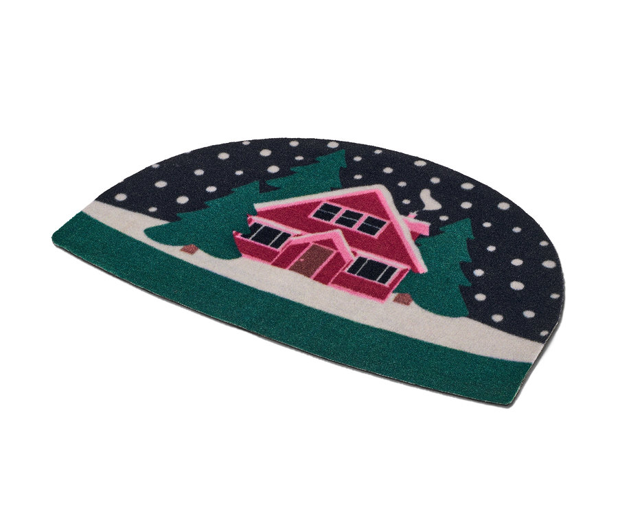 Wycieraczka z motywem zaśnieżonego domu między drzewami.