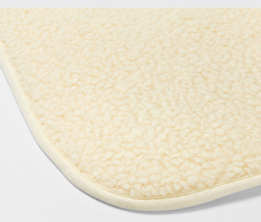 Fragment rogu beżowej maty do jogi z żywą wełną.