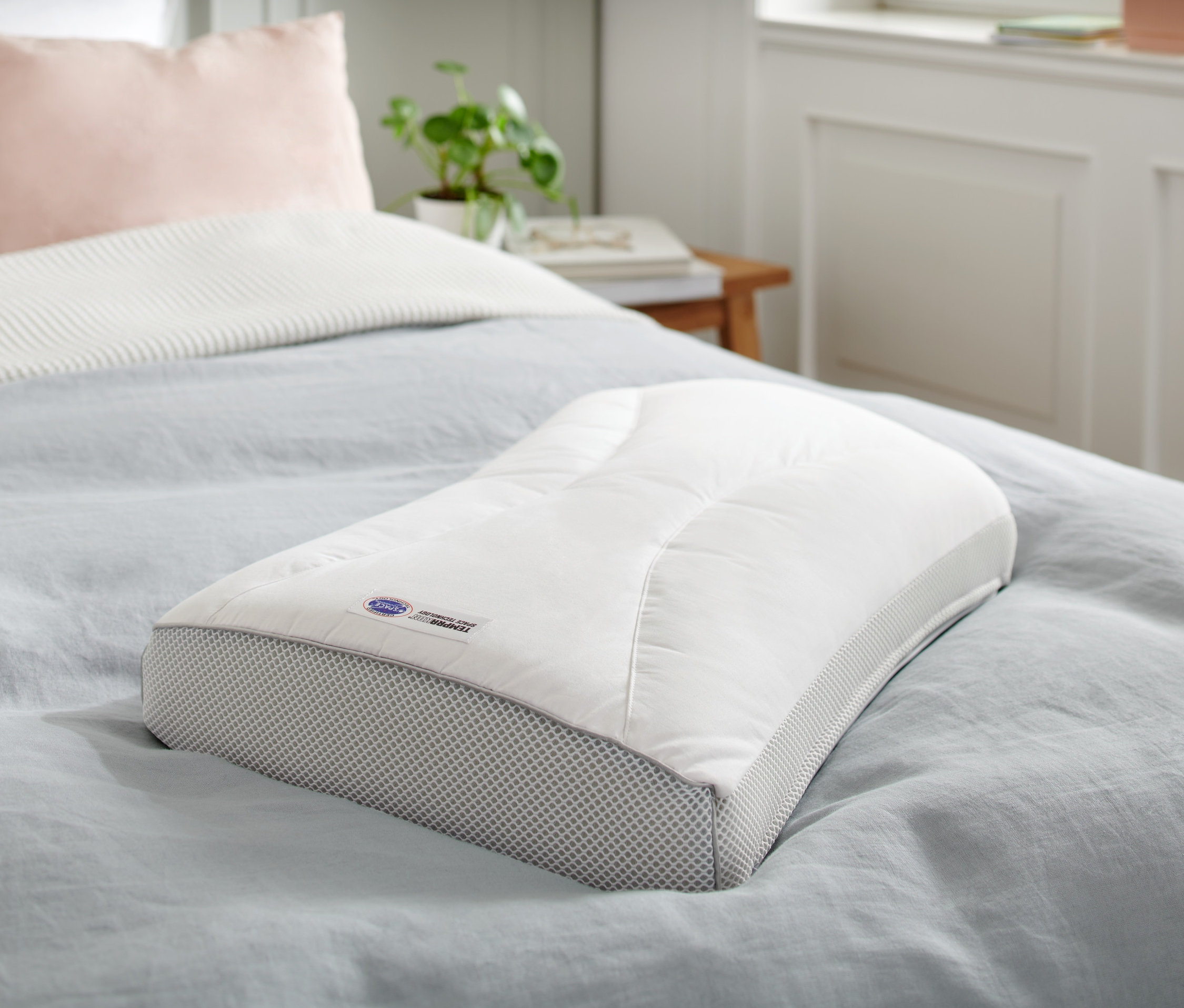 Poduszka Temprakon X-Zone leży na łóżku z niebieską narzutą.