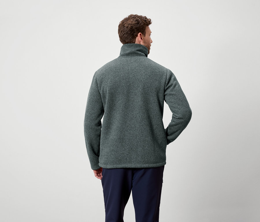 Mężczyzna tyłem do kamery ma na sobie szarozielony polar i granatowe spodnie.