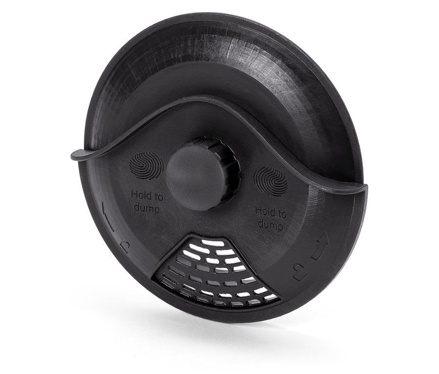 Szczegółowy widok czarnej plastikowej pokrywy z napisem "Hold to dump" i kratką.