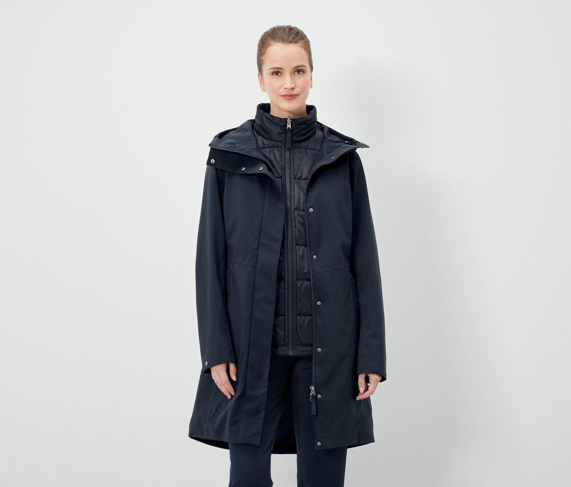 Kobieta ma na sobie granatowy płaszcz i kamizelkę.