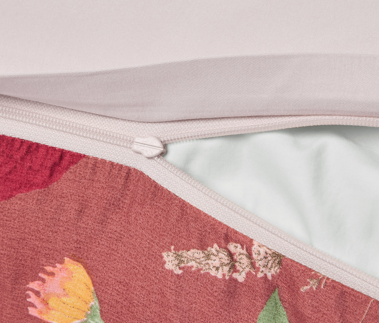 Szczegółowe ujęcie poszewki na poduszkę w kwiatowy wzór z zamkiem błyskawicznym.