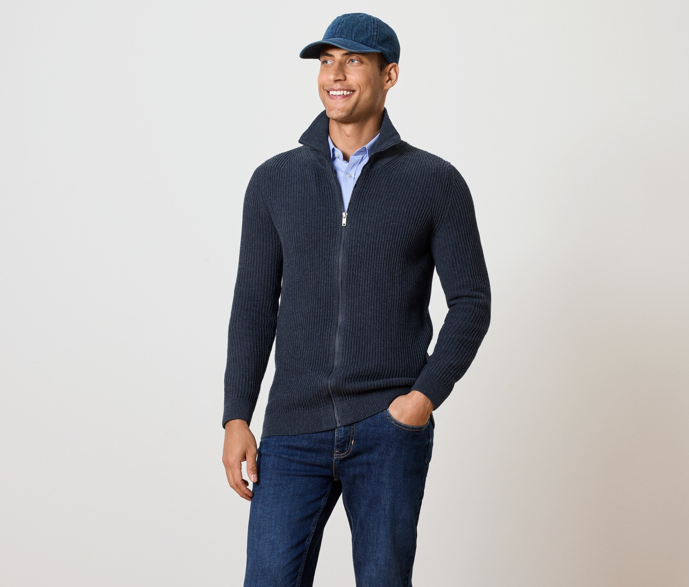 Mężczyzna ma na sobie granatowy rozpinany sweter z dzianiny.