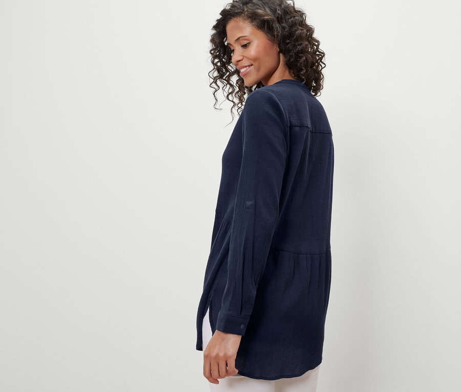 Kobieta ma na sobie granatową, długą bluzkę.