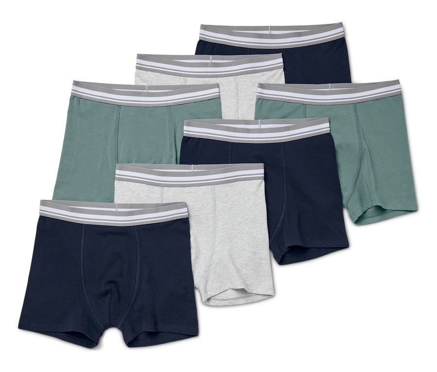 Siedem par bokserek chłopięcych w różnych kolorach leży na białym tle.