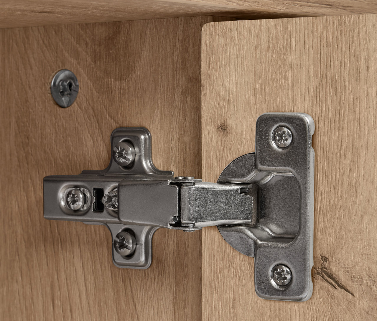 Szczegół srebrnego zawiasu na drewnianym kredensie REET.