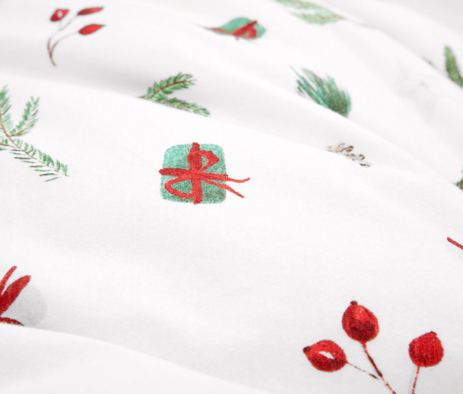 Zbliżenie tkaniny z motywami świątecznymi, zielone gałązki i czerwone jagody.