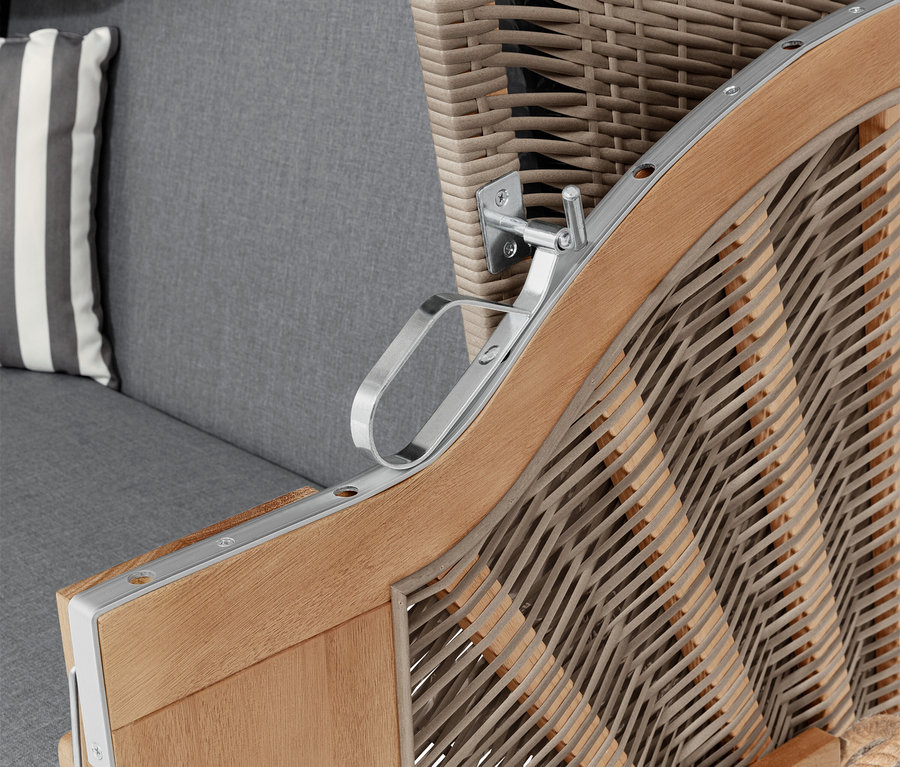 Szczegół kosza plażowego z podłokietnikiem, szarą poduszką i poduszką w paski.