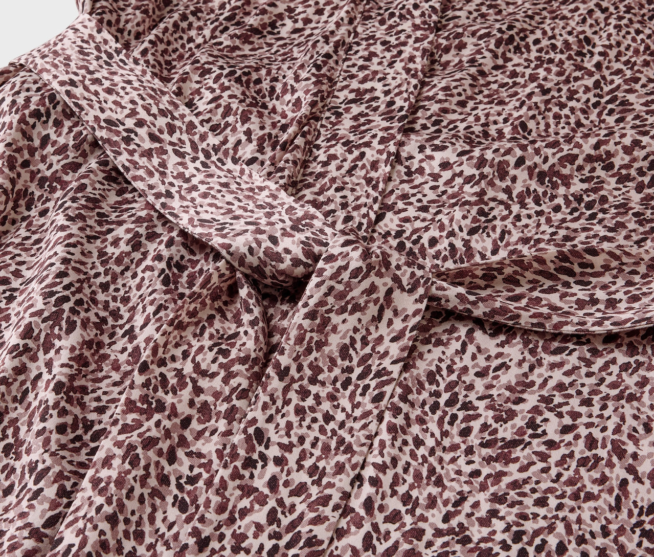 Zbliżenie na tkaninę z brązowym wzorem w plamki i węzłem.