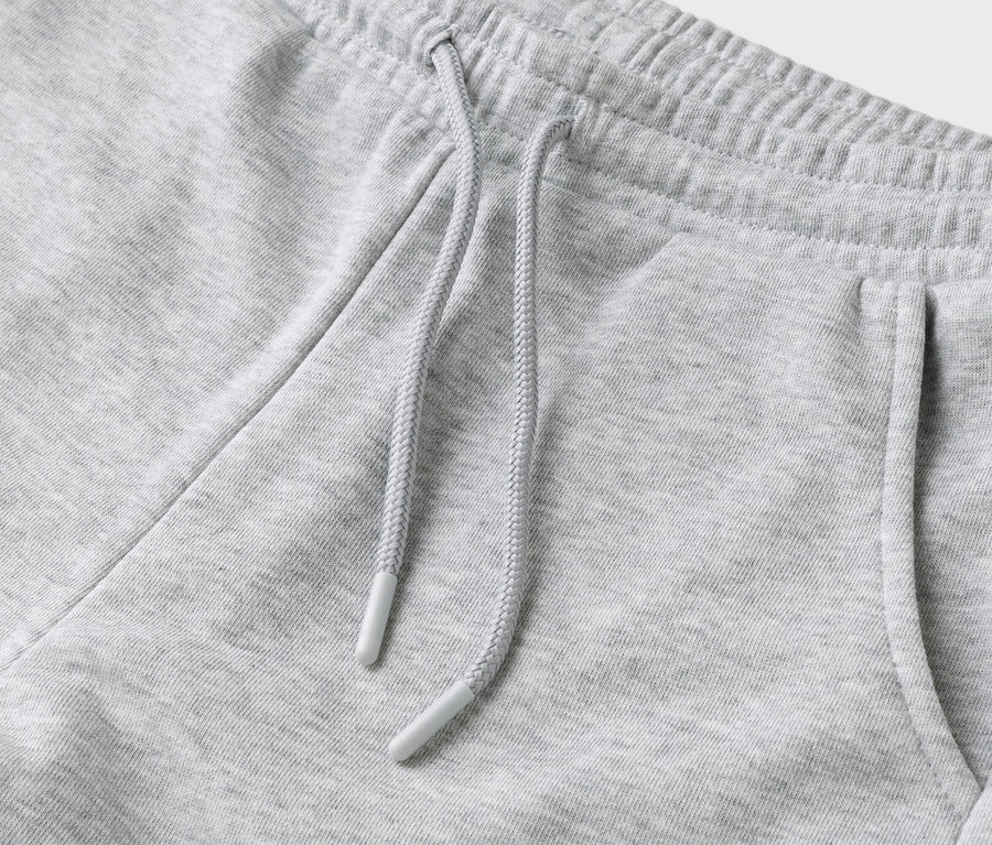 Szczegółowe ujęcie szarych spodni dresowych ze sznurkiem i kieszenią.