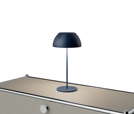 Niebieska lampa stoi na beżowym stole ze srebrnymi akcentami.