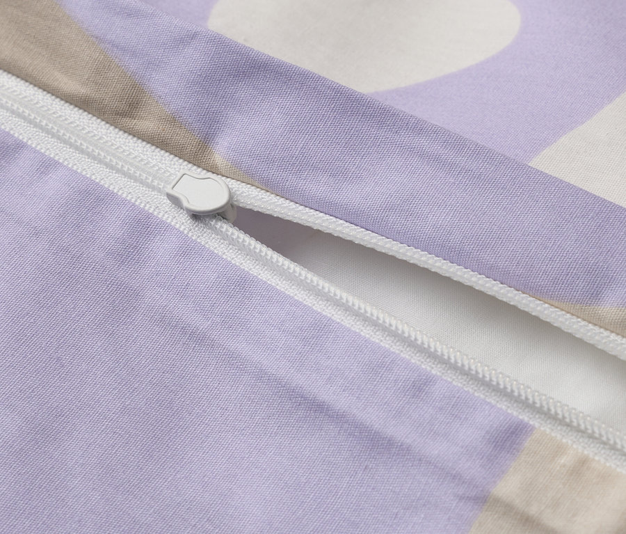 Zbliżenie częściowo otwartej, fioletowej poszwy na kołdrę z białym zamkiem błyskawicznym.