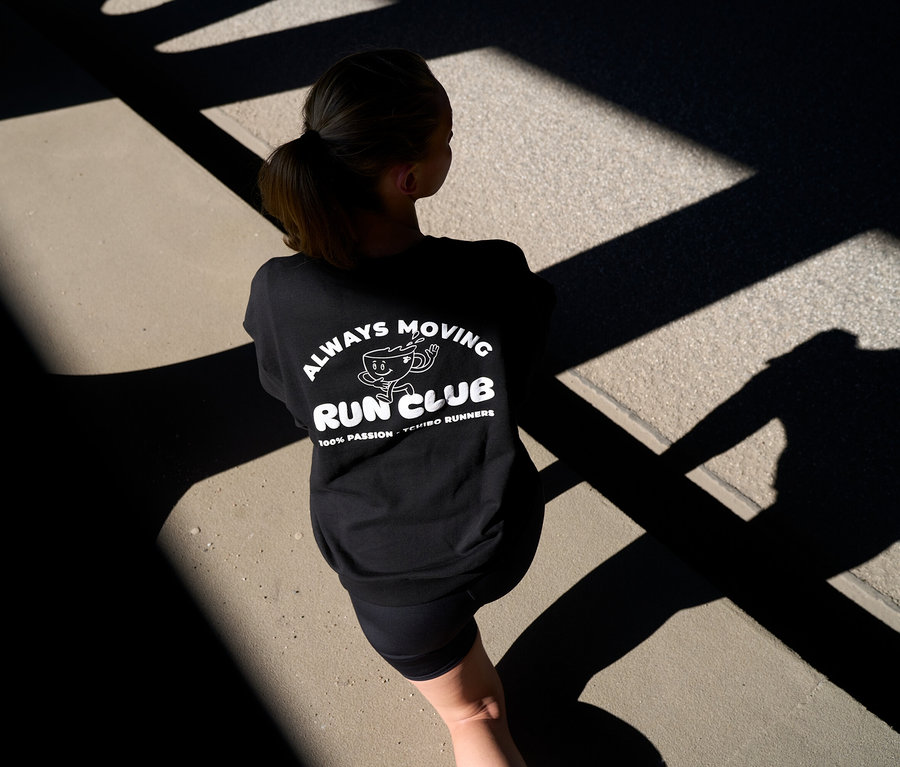 Osoba od tyłu w czarnej bluzie z nadrukiem „RUN CLUB” i krótkich antracytowych legginsach sportowych „ActivePower”.