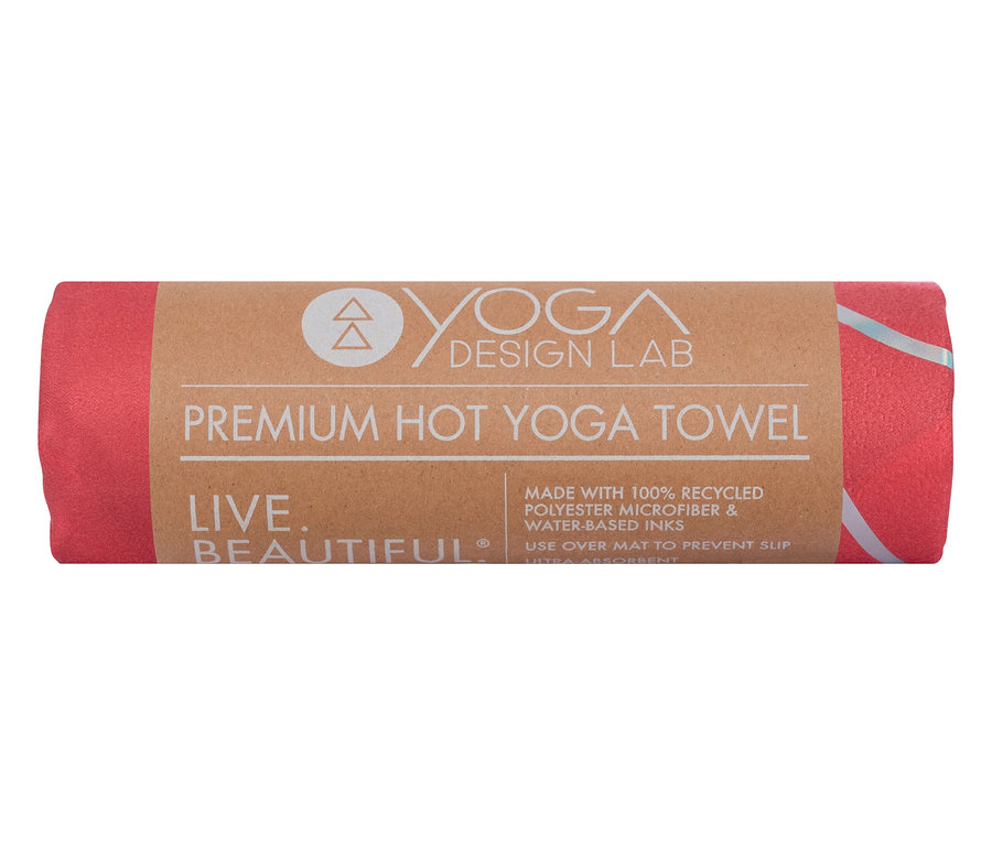 Zwinięty, różowy ręcznik do jogi Premium Hot Yoga marki Yoga Design Lab z brązową banderolą.
