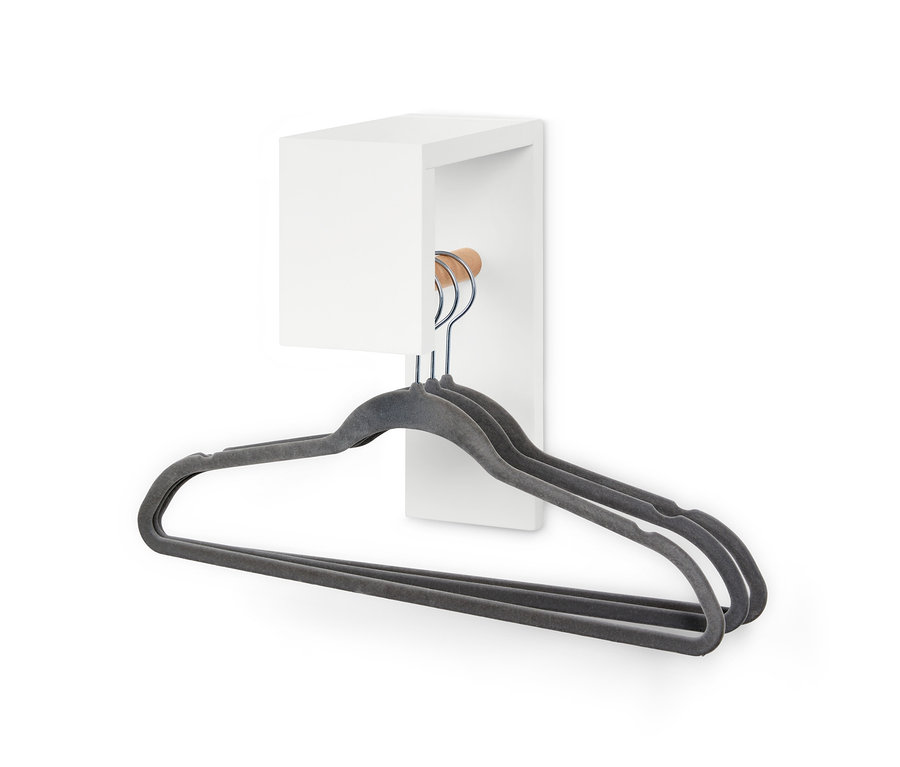 Trzy szare wieszaki wiszą na małej garderobie.