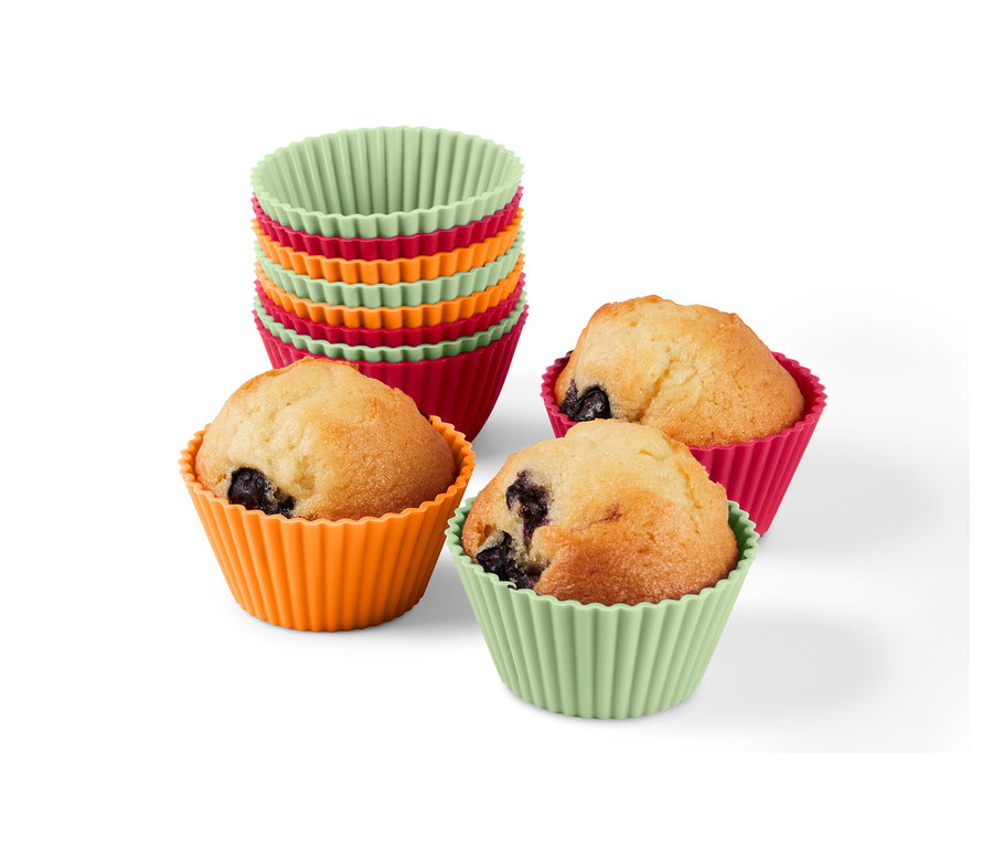 Stos 12 foremek do muffinek i trzy muffiny w foremkach w kolorze pomarańczowym, różowym i zielonym.