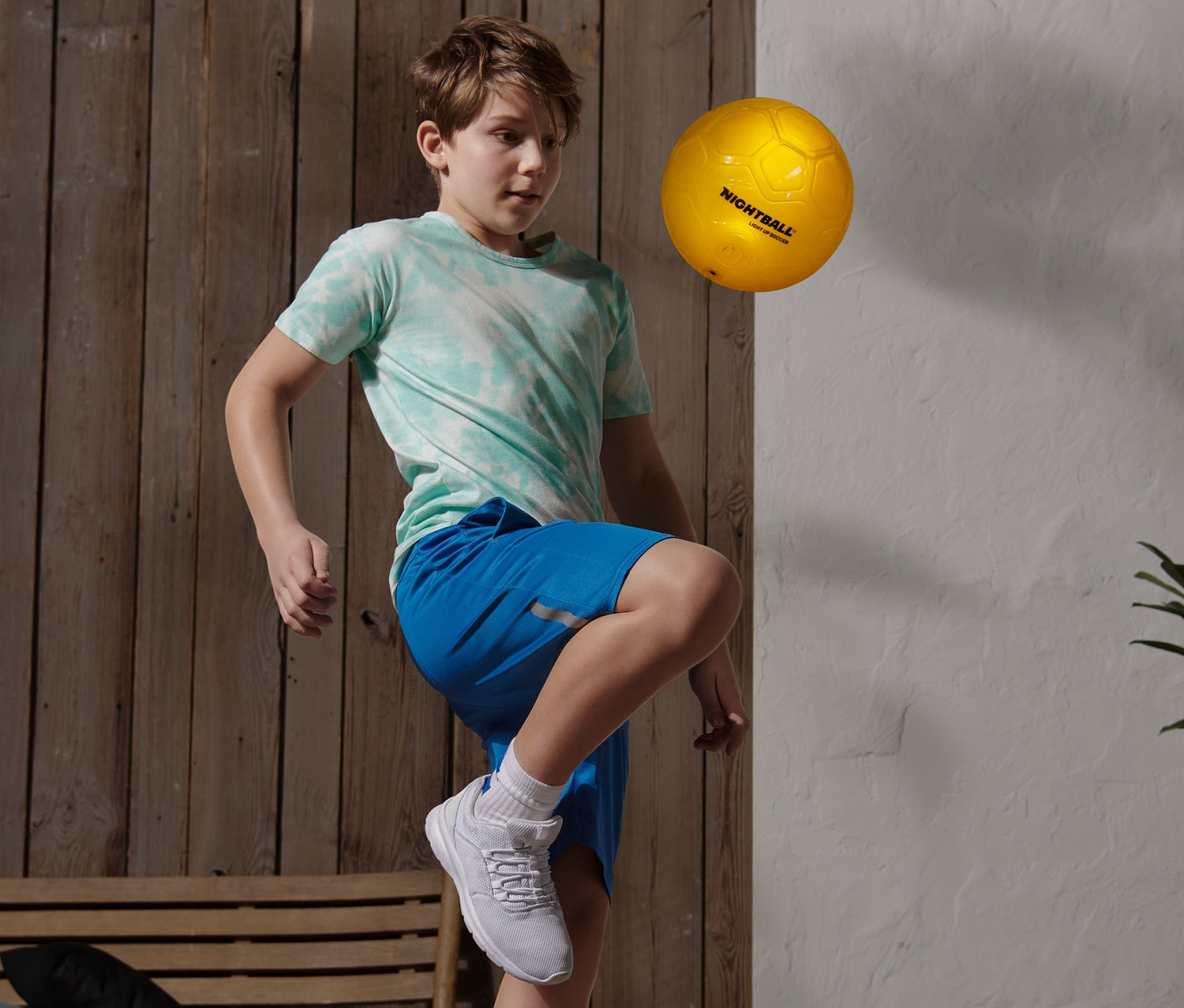 Chłopiec podbija kolanem żółtą piłkę LED »NightBall«.