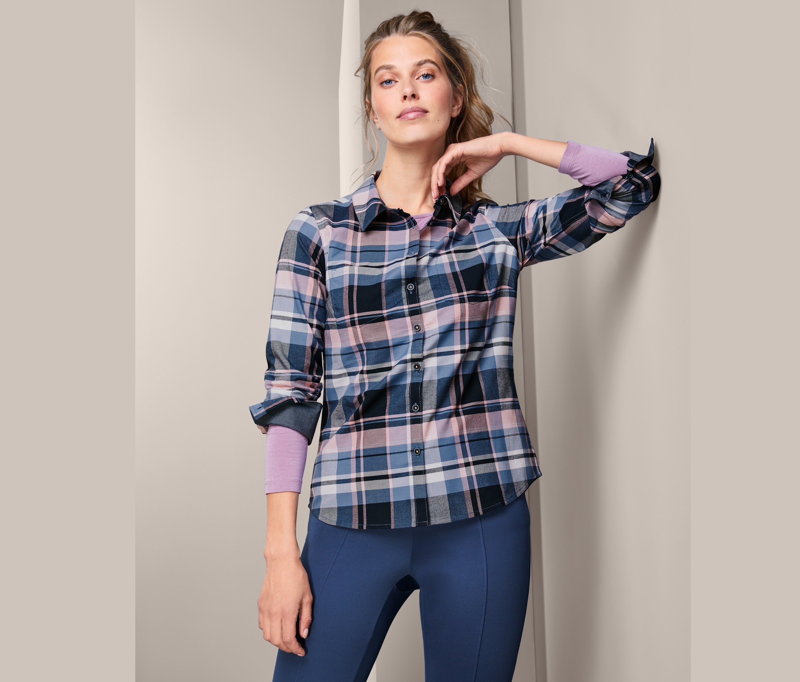 Kobieta pozuje w damskiej, flanelowej koszuli w kratkę.