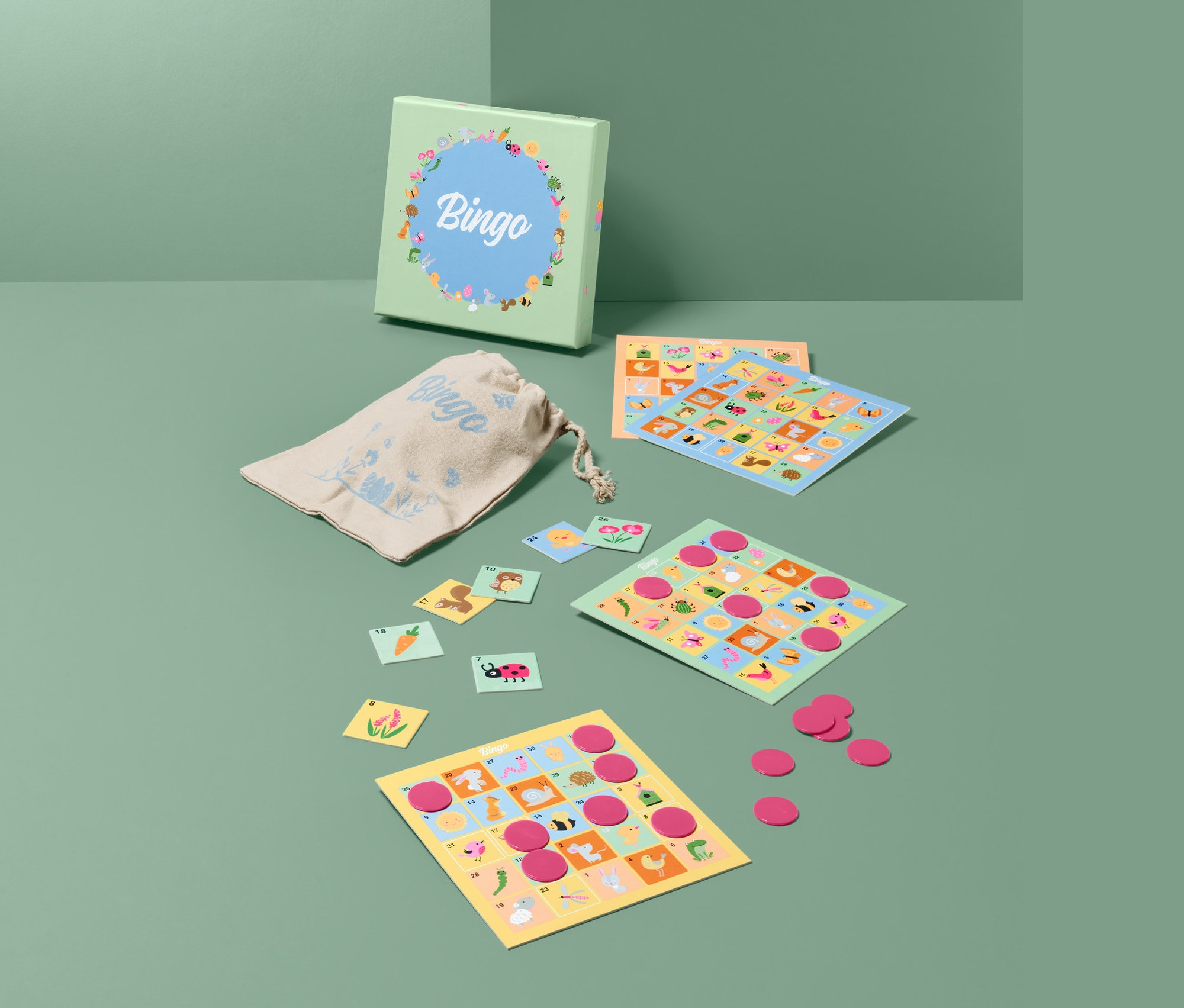 Rozłożona gra planszowa »Wielkanocne bingo« z kartami, żetonami i woreczkiem na zielonym tle.