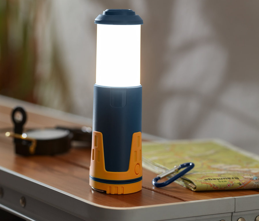 Na stole stoi teleskopowa lampa kempingowa.