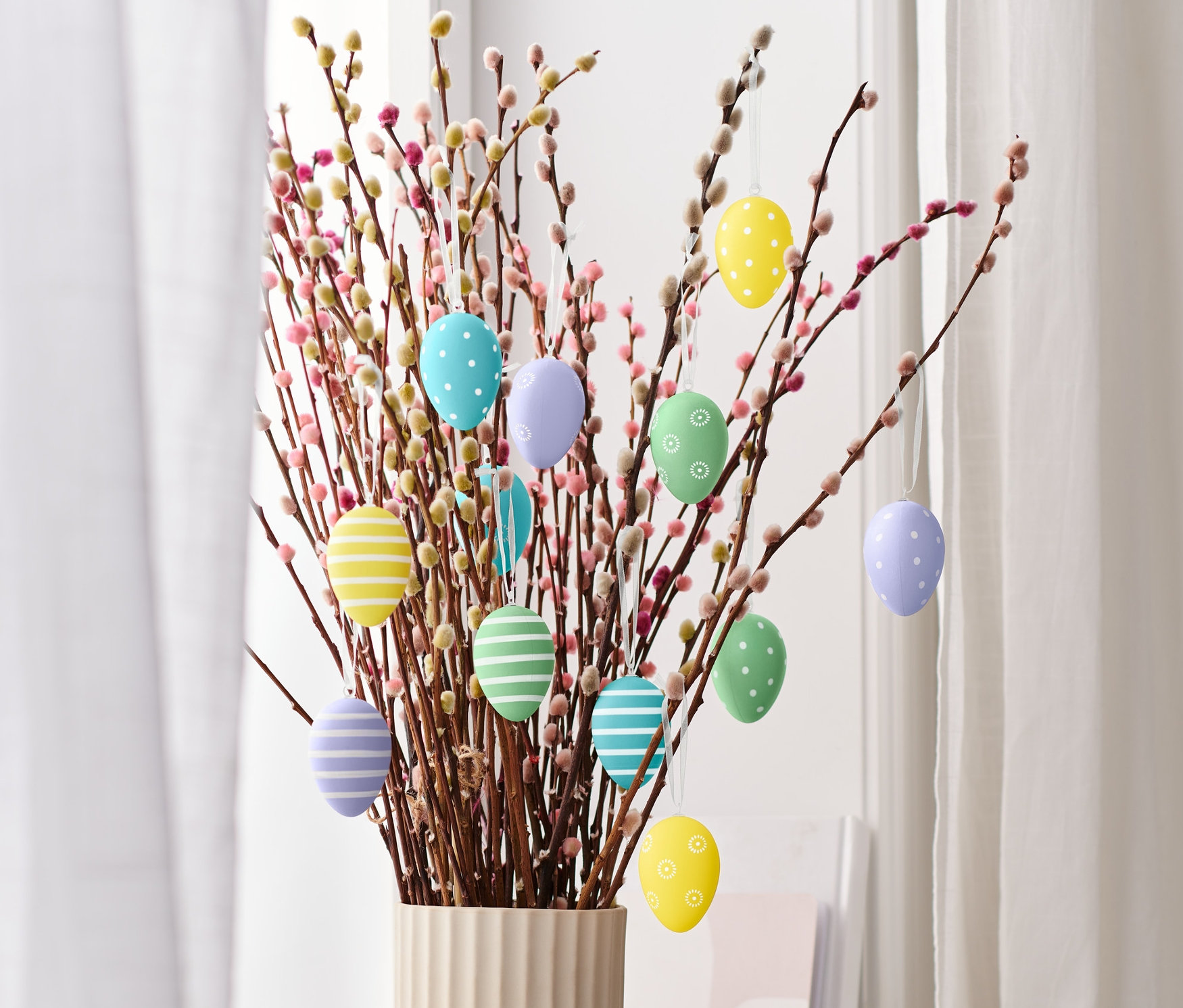 Bukiet bazi kotek z 12 dekoracyjnymi jajkami wielkanocnymi.