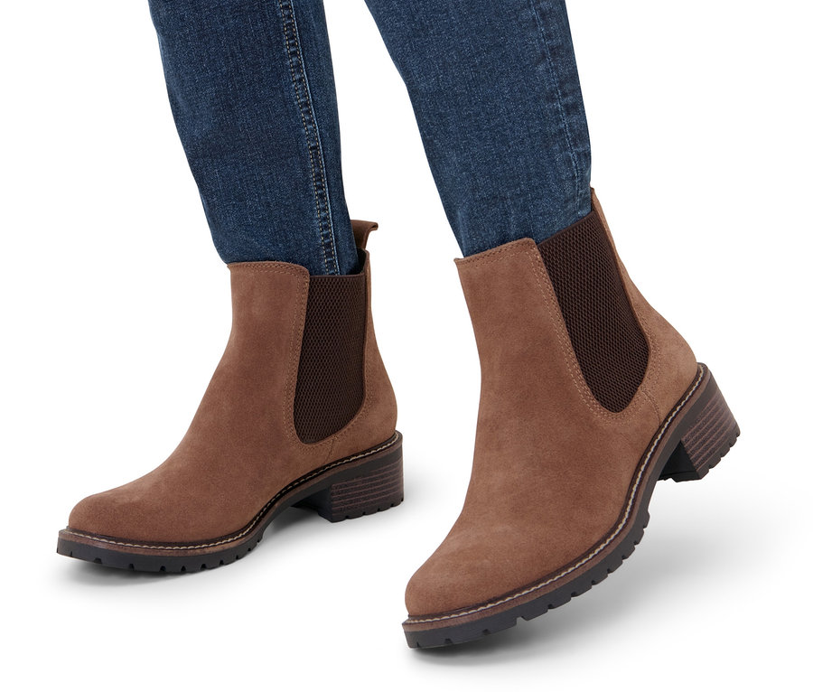 Nogi w dżinsach w zamszowych botkach.