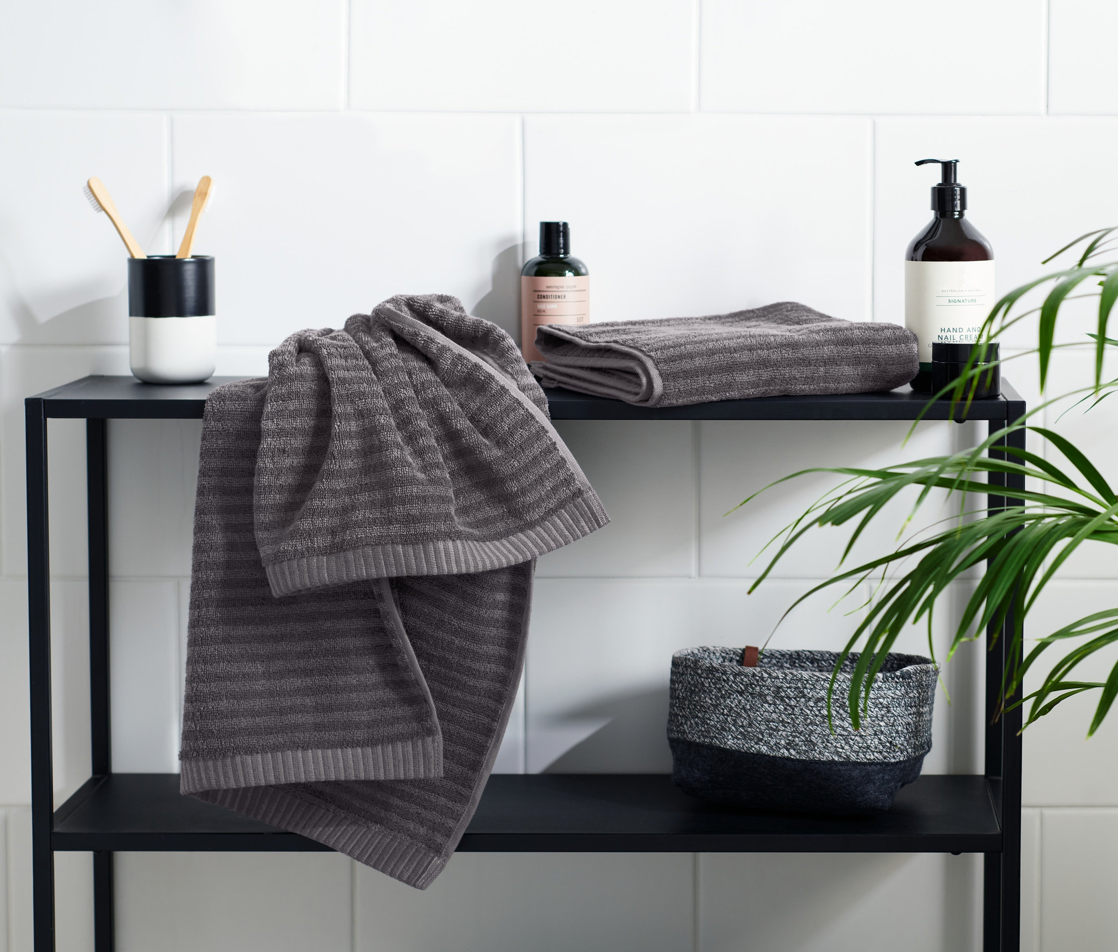 Na czarnej półce leżą 2 antracytowe ręczniki.