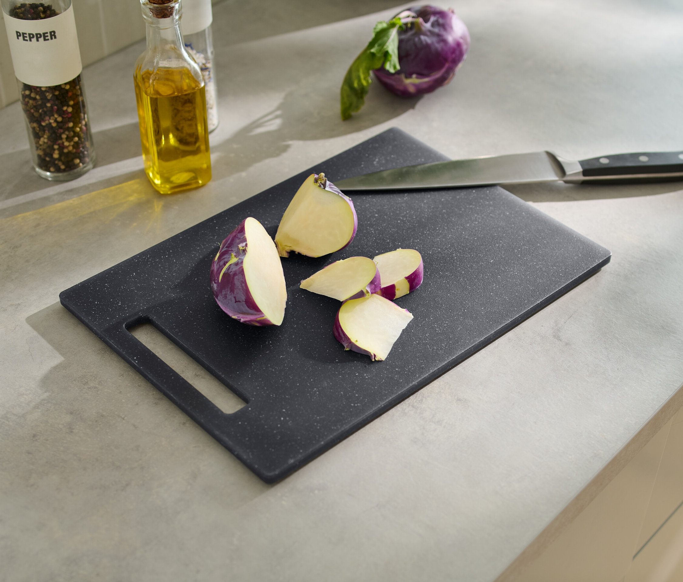 Pokrojona fioletowa rzodkiewka na desce do krojenia z imitacji granitu z nożem.