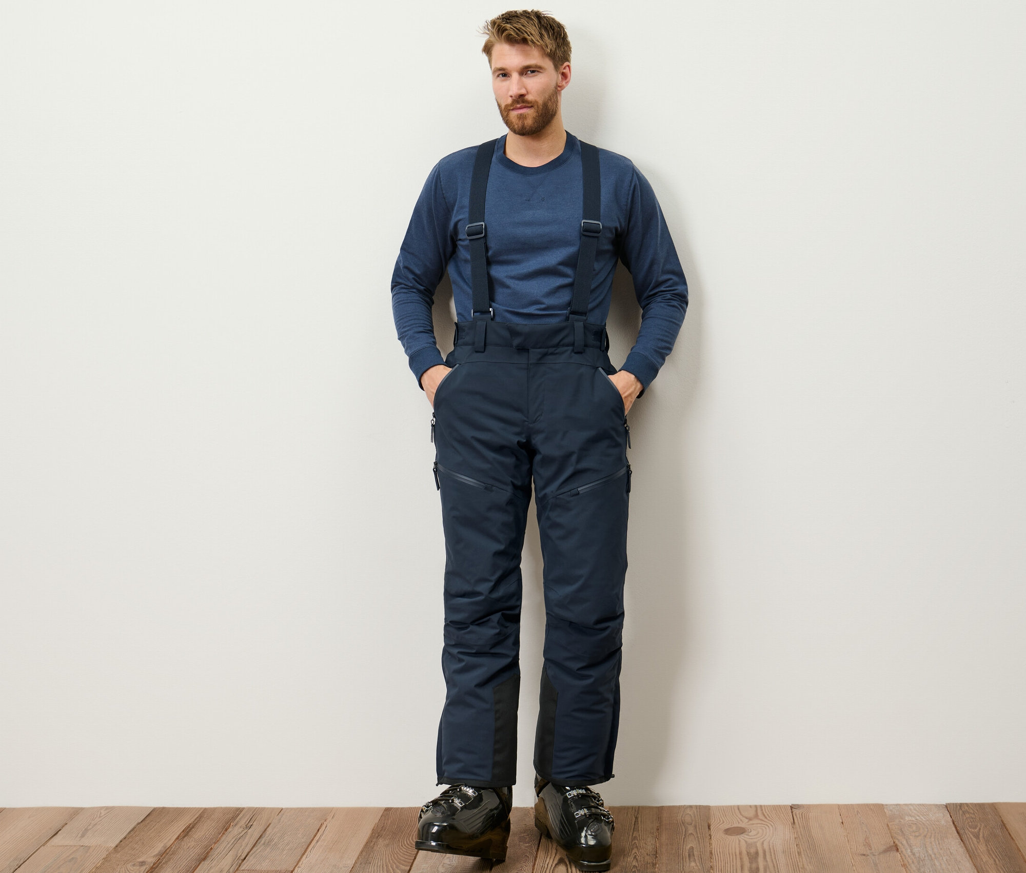 Mężczyzna stoi i ma na sobie niebieskie profesjonalne spodnie narciarskie.