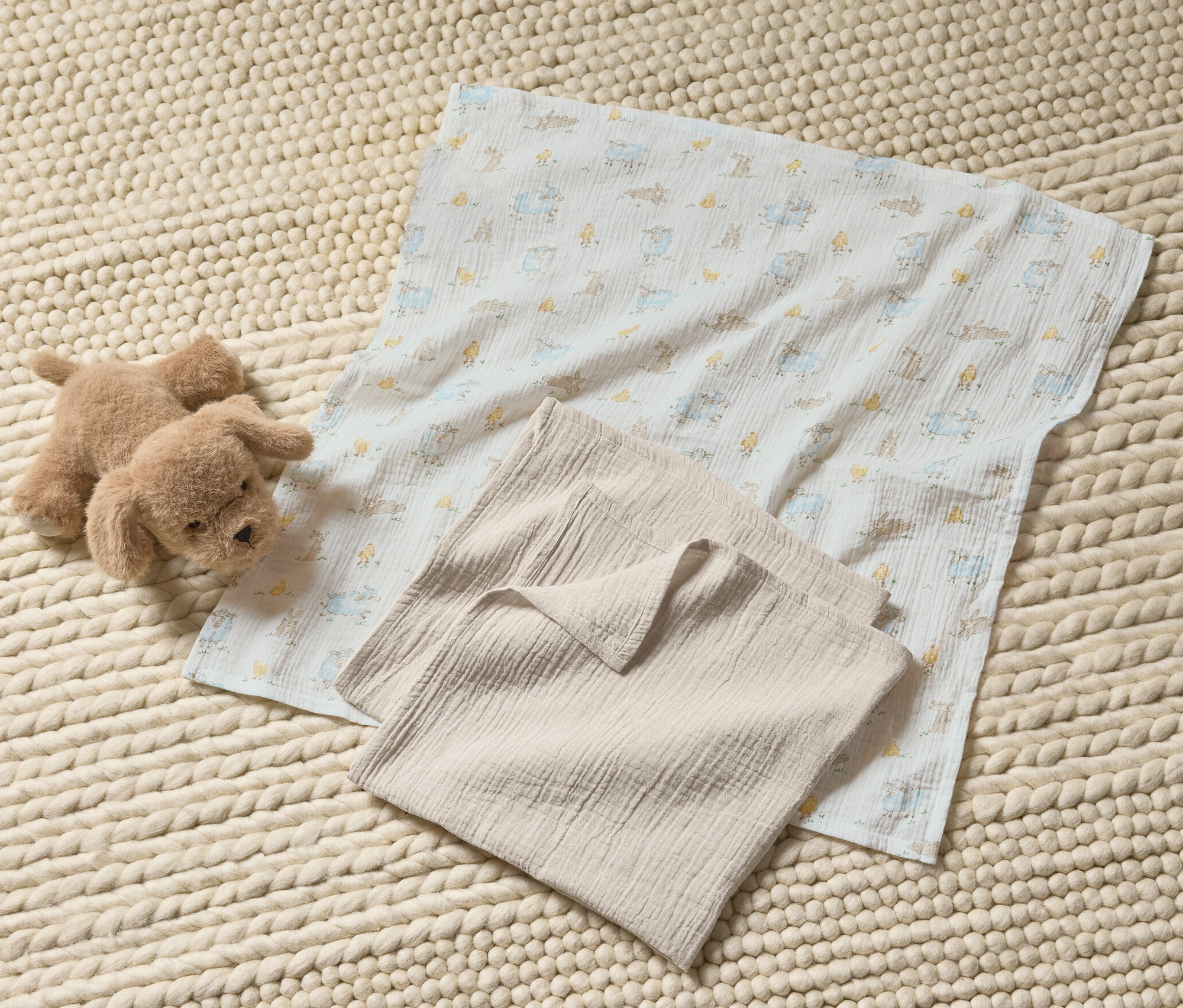 Pluszowy pies i chusteczki muślinowe (3 sztuki) na dzierganym dywanie.