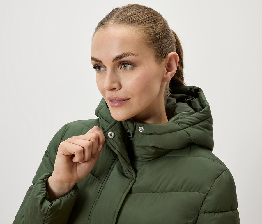 Kobieta zapina oliwkowozieloną kurtkę puchową z kapturem.