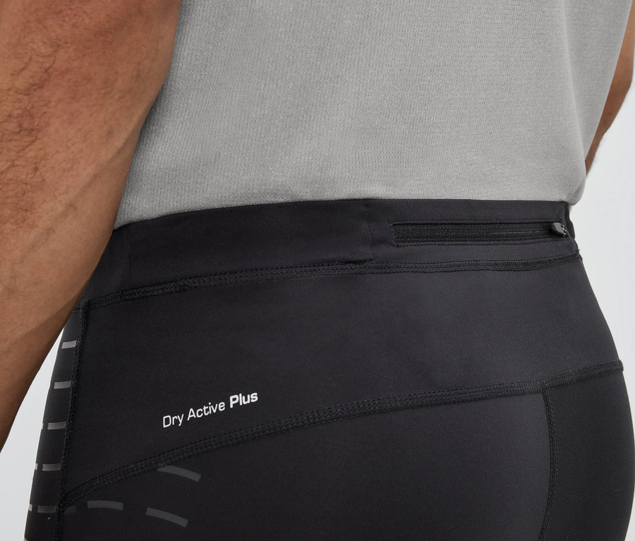 Mężczyzna ma na sobie czarne legginsy z napisem Dry Active Plus i kieszenią na zamek błyskawiczny w pasie.