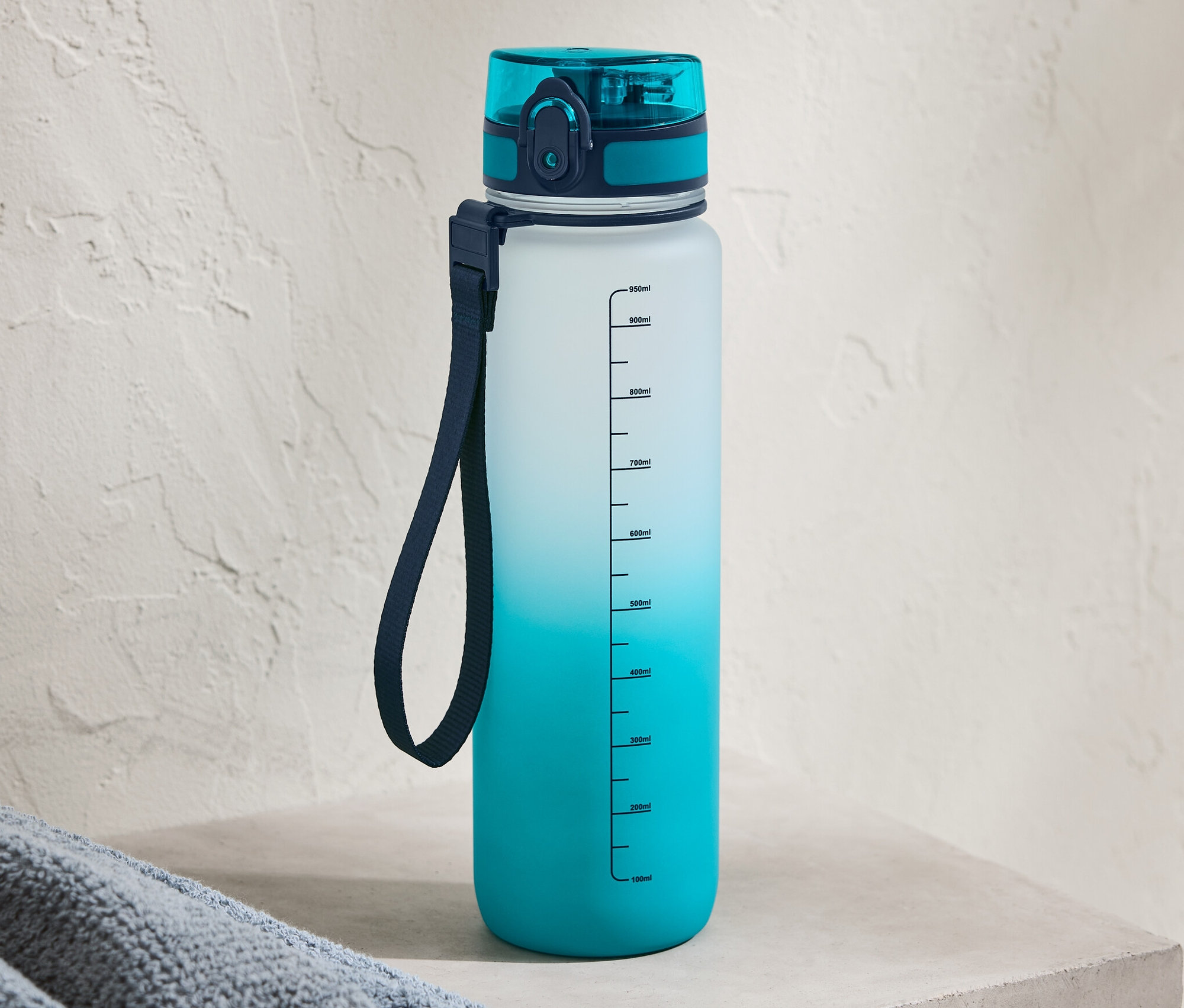 Niebieski bidon z gradientem kolorów stoi na betonowej półce.