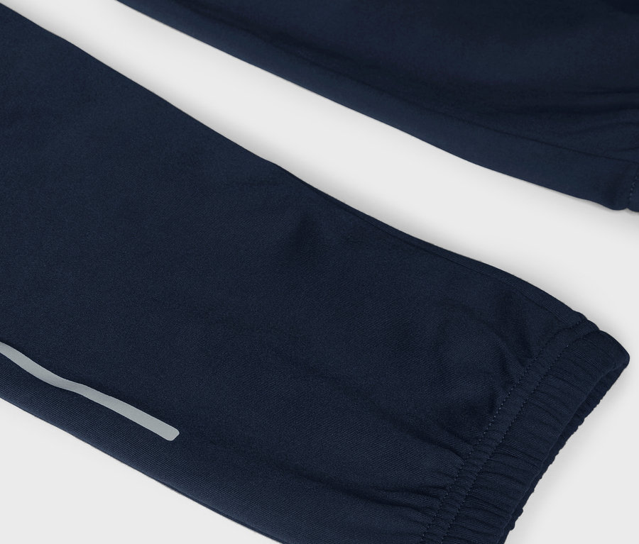 Szczegół granatowych spodni dresowych z odblaskowym paskiem.