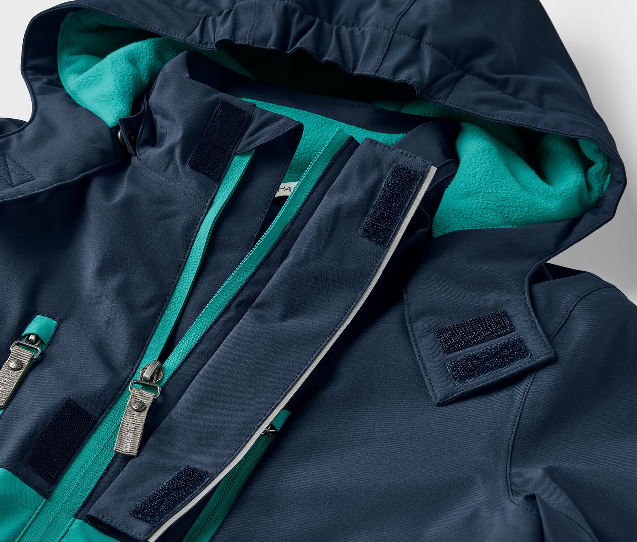 Zbliżenie na granatową kurtkę z kapturem i zielonym zamkiem błyskawicznym.