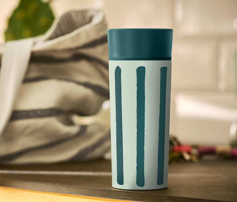 Kubek Coffee-to-go w paski stoi na stole.