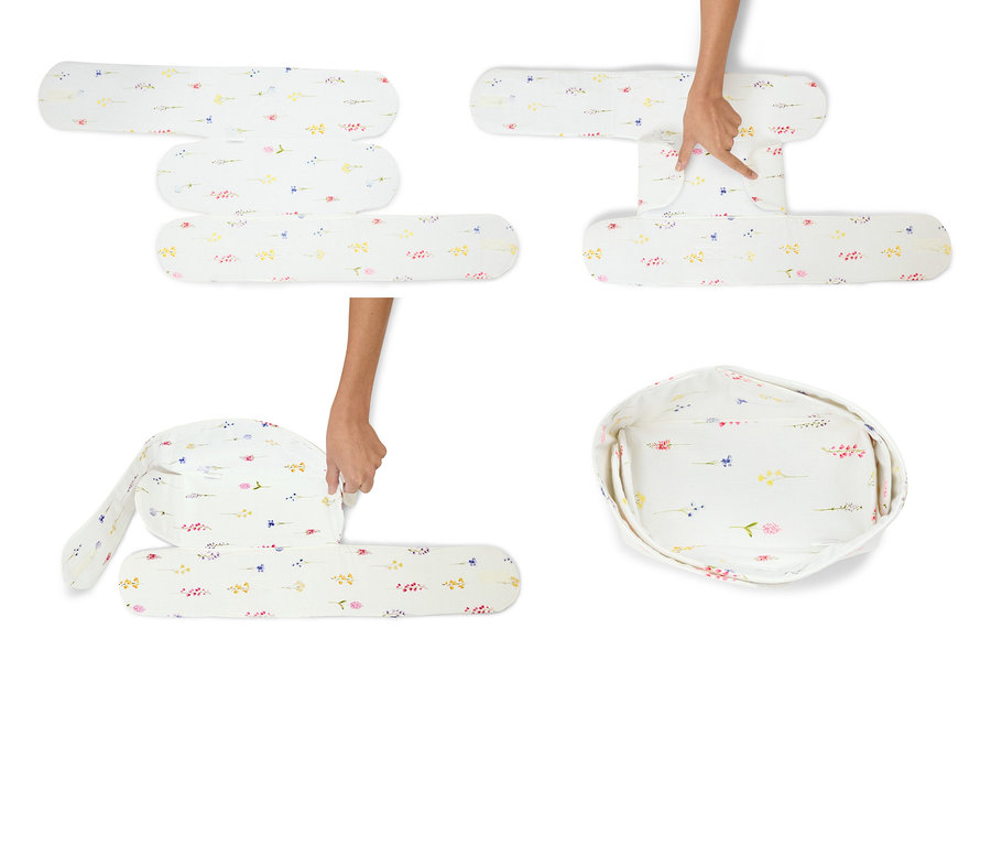 Ręce składają białe leżaczek dla niemowląt we wzory kwiatowe.