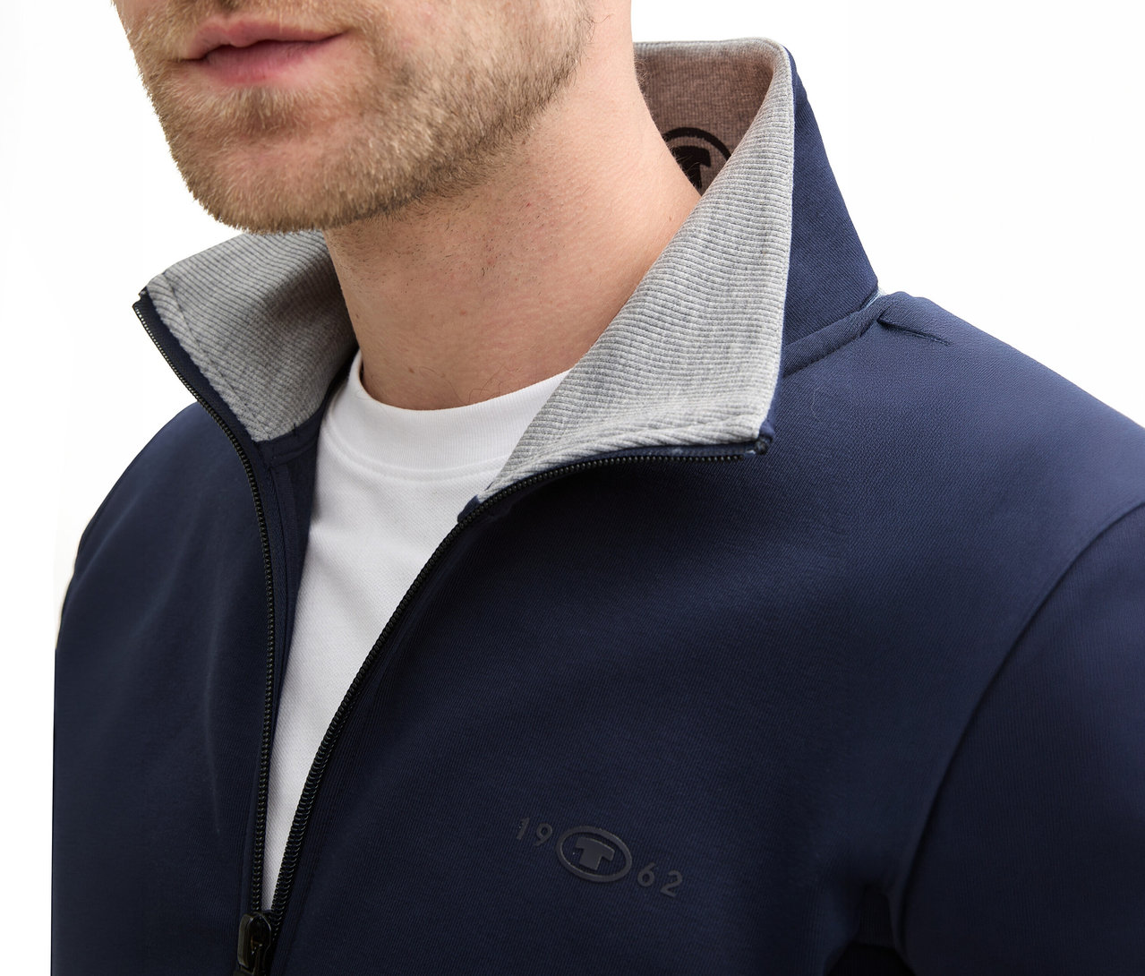 Zbliżenie mężczyzny z brodą w granatowej bluzie dresowej ze stójką Tom Tailor, Sky Captain Blue.